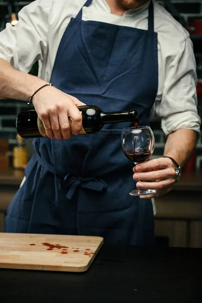 Man Blue Apron White Shirt Standing Kitchen Opens Bottle Red Стоковое Фото