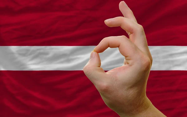 Ok geste devant le drapeau national latvia — Photo