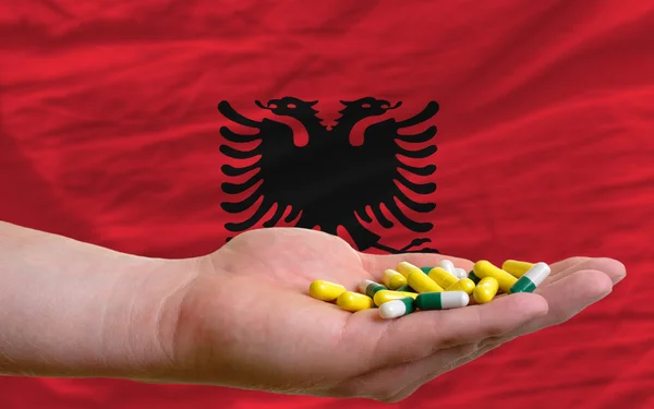 Anläggningen piller i handen framför Albanien flagga — Stockfoto