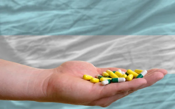 Sosteniendo pastillas en la mano frente a la bandera nacional argentina —  Fotos de Stock