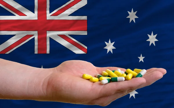 Holding pills in hand in front of australia national flag — Stock Photo, Image