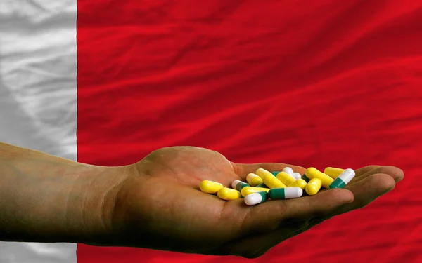 Holding pills in hand in front of bahrain national flag — Stock Photo, Image