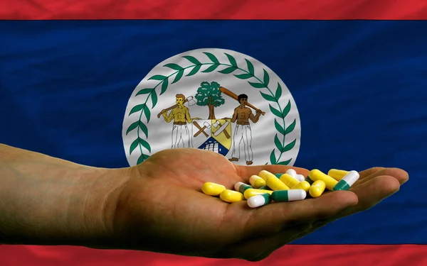 Tenant des pilules en main devant le drapeau national du Belize — Photo
