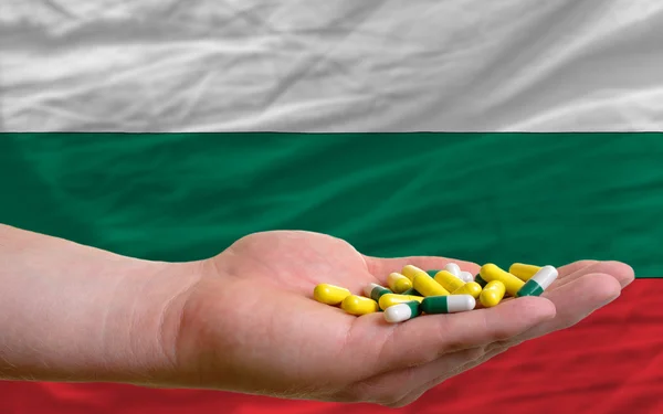 Sosteniendo pastillas en la mano frente a la bandera nacional bulgaria — Foto de Stock