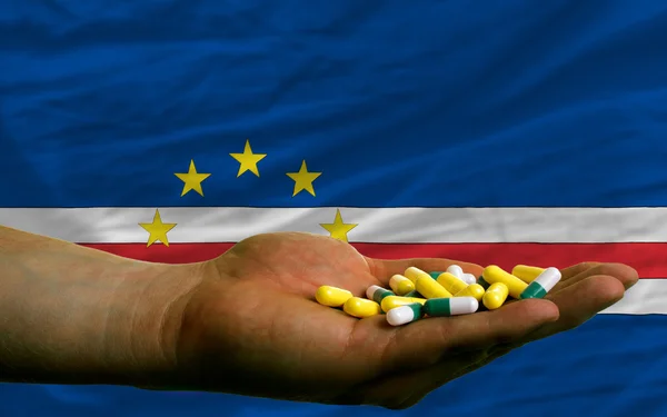 Holding pills in hand in front of capeverde national flag — Stock Photo, Image