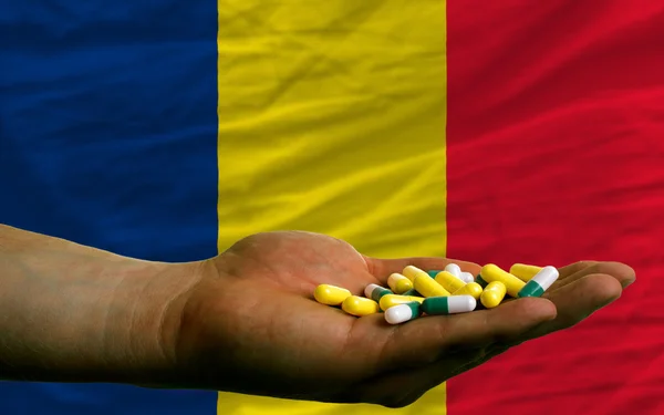 Holding pills in hand in front of chad national flag — Stock Photo, Image