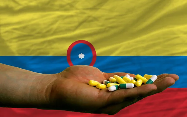 Holding pills in hand in front of colombia national flag — Stock Photo, Image