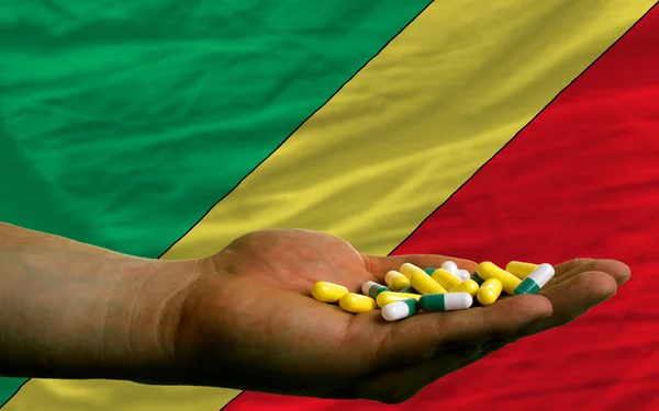 Sosteniendo pastillas en la mano frente a la bandera nacional congo —  Fotos de Stock