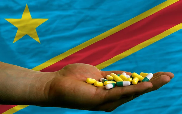 Tabletten in der Hand vor der Nationalflagge des Kongo — Stockfoto