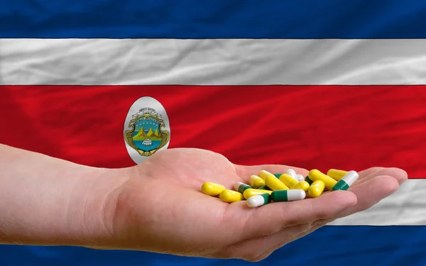 Holding pills in hand in front of costa rica national flag — Stock Photo, Image