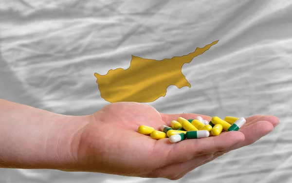 Holding pills in hand in front of cyprus national flag — Zdjęcie stockowe