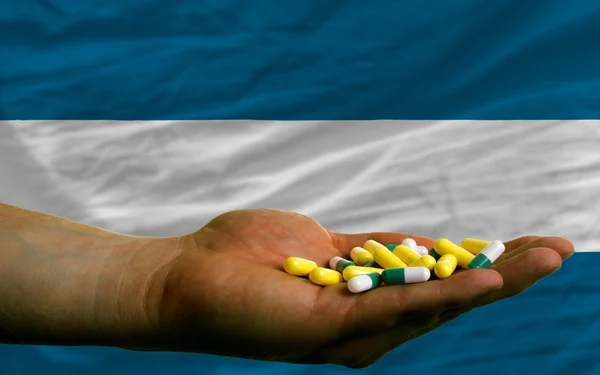 Holding pills in hand in front of el salvador national flag — Stock Photo, Image