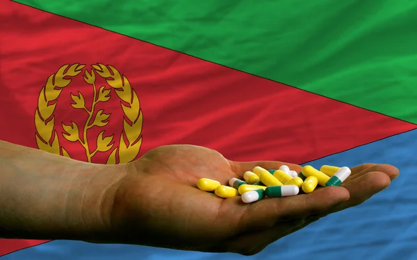 Holding pills in hand in front of eritrea national flag — Stock Photo, Image