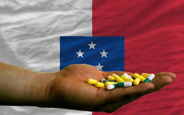 Holding pills in hand in front of franceville national flag — Stock Photo, Image