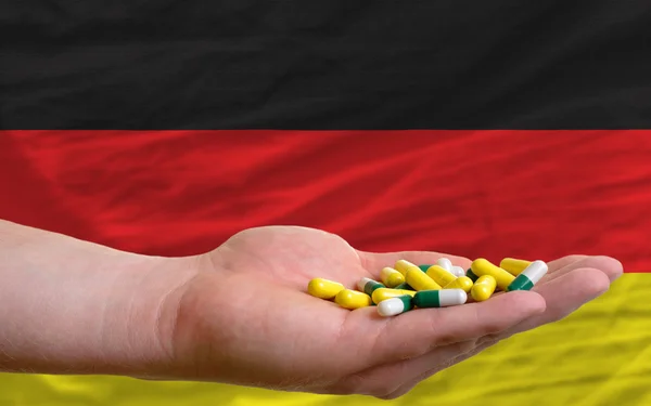 Sosteniendo pastillas en la mano frente a la bandera nacional de Alemania — Foto de Stock