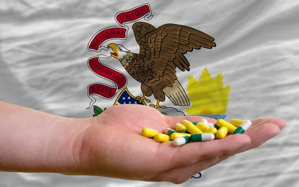 Тримаючи таблетки в руці перед Іллінойсом американський державний прапор — стокове фото