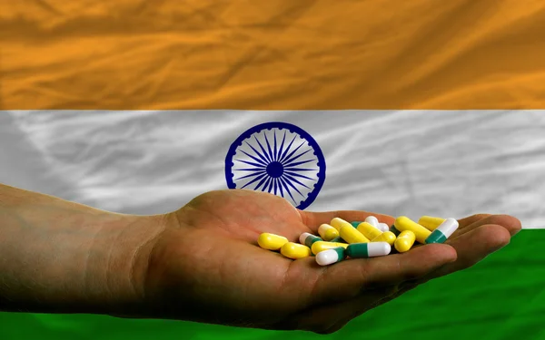 Sosteniendo pastillas en la mano frente a la bandera nacional de la India — Foto de Stock