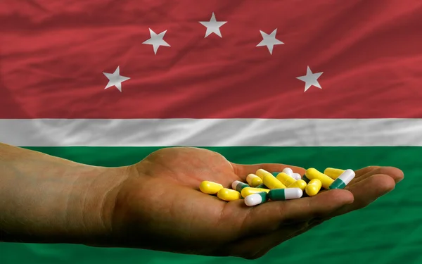 Holding pills in hand in front of maghreb national flag — Stock Photo, Image