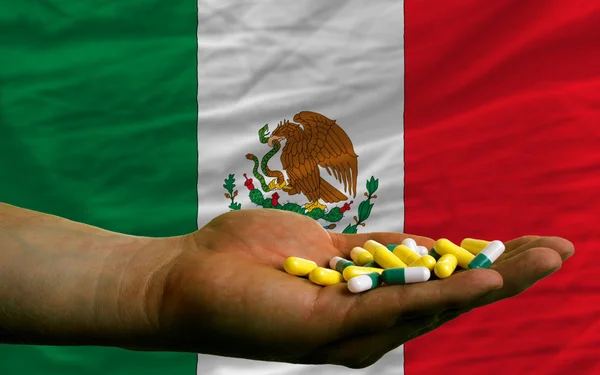 Holding pills in hand in front of mexico national flag — Stock Photo, Image