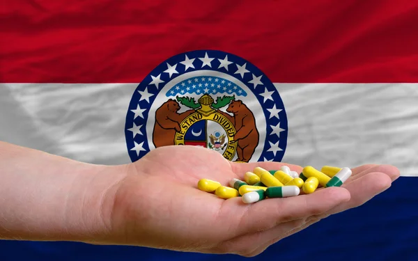 Holding pills in hand in front of missouri us state flag — Stock Photo, Image