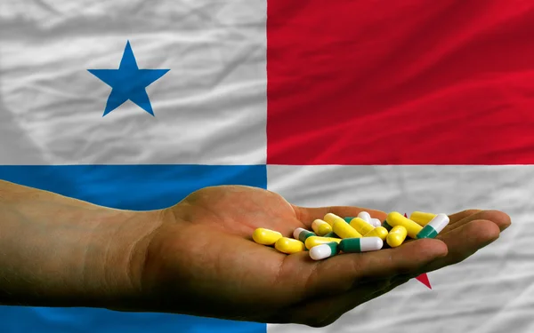 Держа в руках таблетки перед национальным флагом Панамы — стоковое фото