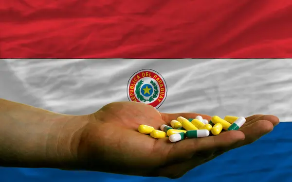 पैराग्वे राष्ट्रीय ध्वज के सामने हाथ में गोलियां पकड़ते हुए — स्टॉक फ़ोटो, इमेज