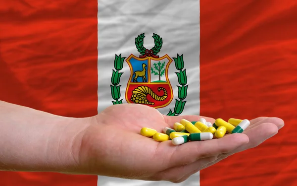 Tenendo le pillole in mano davanti alla bandiera nazionale del Perù — Foto Stock