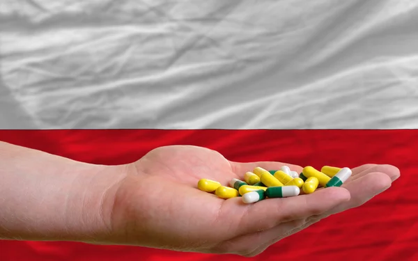 Holding pills in hand in front of poland national flag — Stock Photo, Image