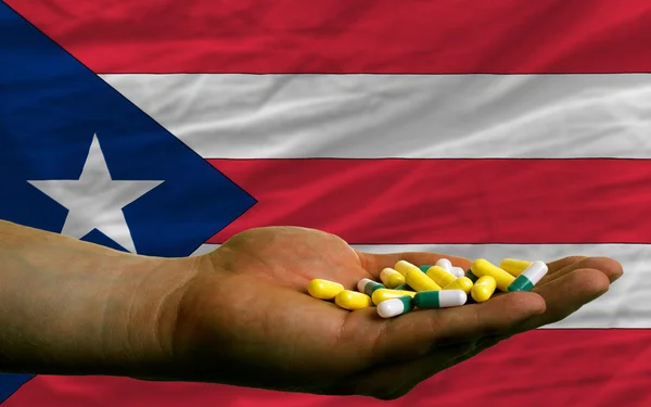 Holding pills in hand in front of puertorico national flag — Stock Photo, Image