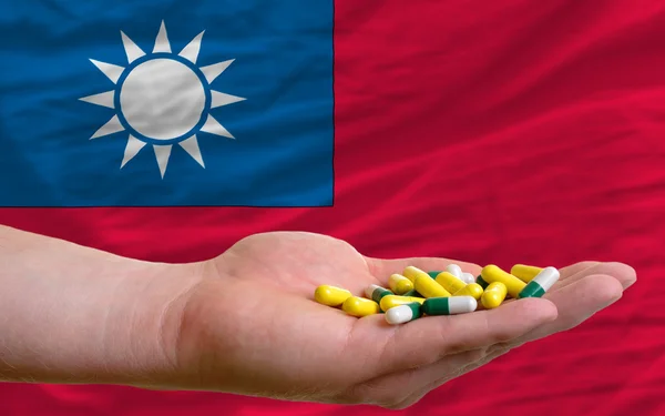 Holding pills in hand in front of taiwan national flag — Stock Photo, Image