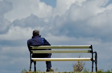 Bulutların içine izlerken bir bankta oturan adam