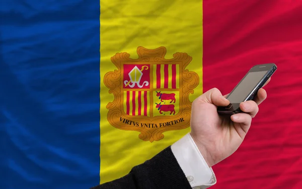 Мобильный телефон перед национальным флагом андорры — стоковое фото