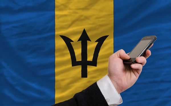 Teléfono celular frente a bandera nacional de barbados —  Fotos de Stock