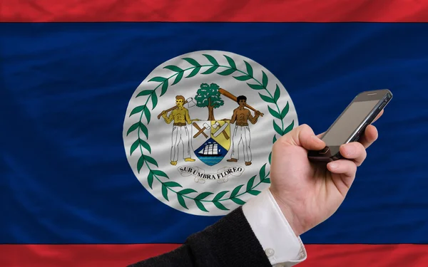 Handy vor Nationalflagge von Belize — Stockfoto