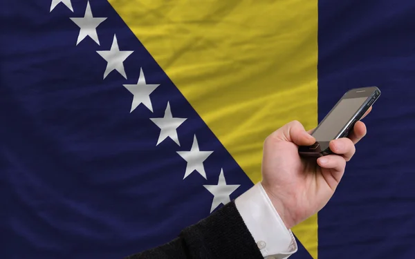 Мобильный телефон перед национальным флагом Боснии и Герцеговины — стоковое фото