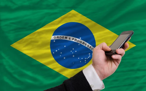 Telefone celular na frente da bandeira nacional do brasil — Fotografia de Stock
