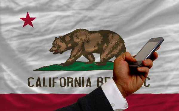Teléfono celular en frente de la bandera del estado americano de California — Foto de Stock