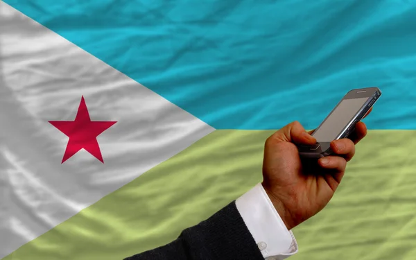 Мобильный телефон перед национальным флагом Джибути — стоковое фото
