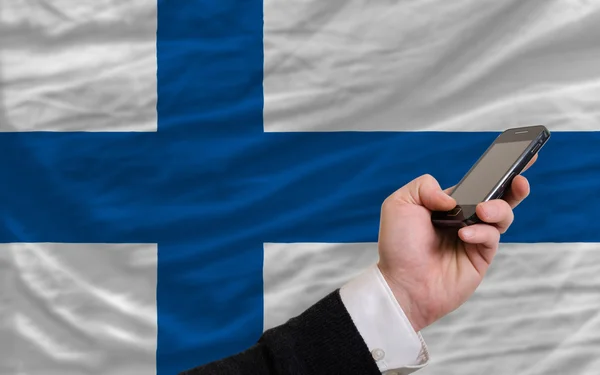 Мобильный телефон перед национальным флагом Финляндии — стоковое фото