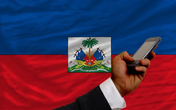 Mobiltelefon i främre nationella flagga i haiti — Stockfoto