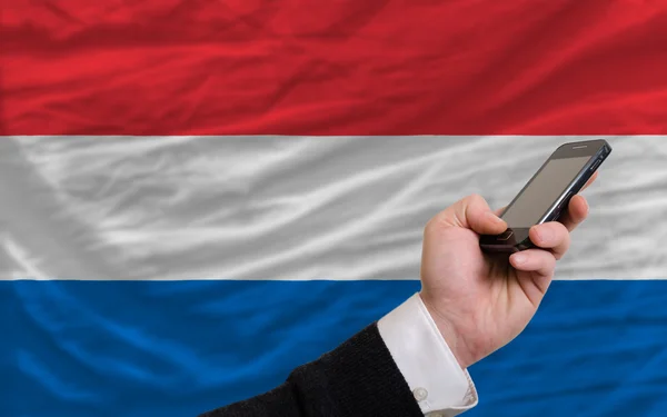 Teléfono celular frente a la bandera nacional de Holanda — Foto de Stock