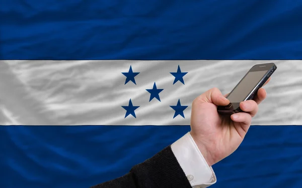 Telefone celular na frente bandeira nacional de honduras — Fotografia de Stock