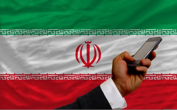 Teléfono celular frente a la bandera nacional de Irán —  Fotos de Stock