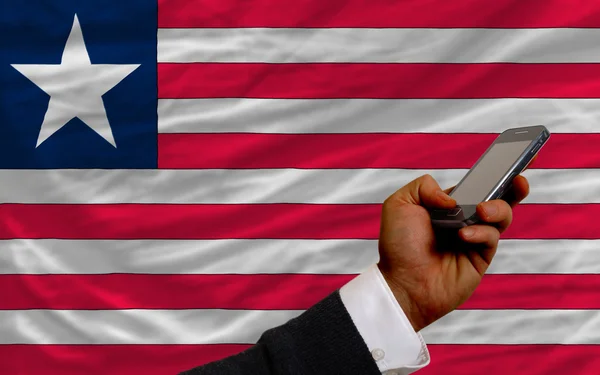 Cell phone in front national flag of liberia — Stock Photo, Image