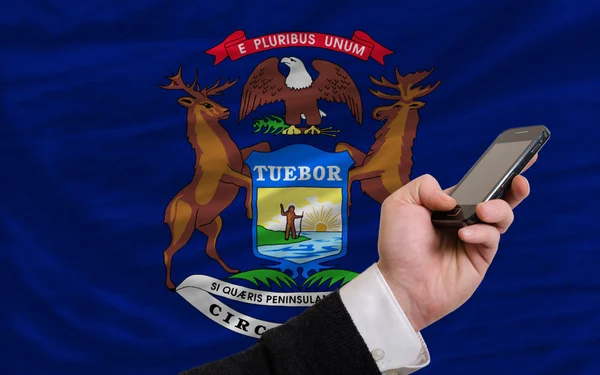Сотовый телефон перед флагом американского штата Мичиган — стоковое фото