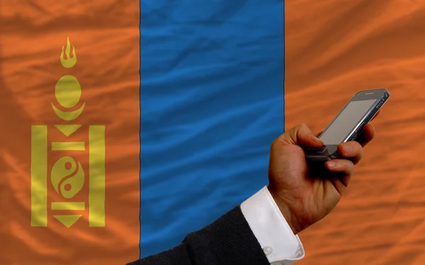 Мобильный телефон перед национальным флагом Монголии — стоковое фото