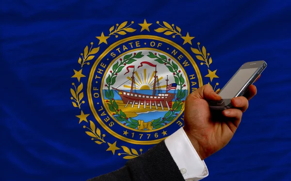 Handy vor Flagge des amerikanischen Bundesstaates New Hampshire — Stockfoto