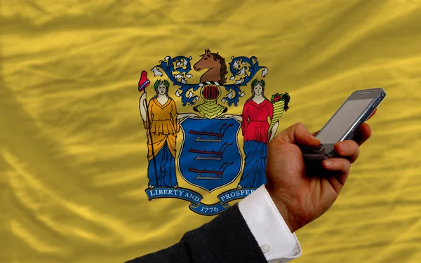 Teléfono celular en frente de la bandera del estado americano de Nueva Jersey —  Fotos de Stock