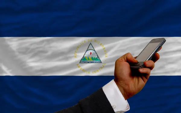 Teléfono celular frente a bandera nacional de nicaragua — Foto de Stock