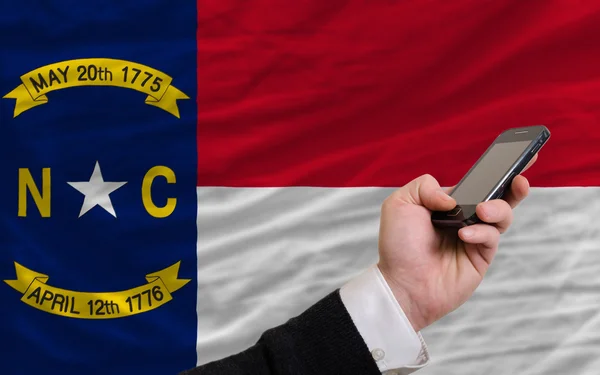 Teléfono celular en frente de la bandera del estado americano de Carolina del Norte — Foto de Stock